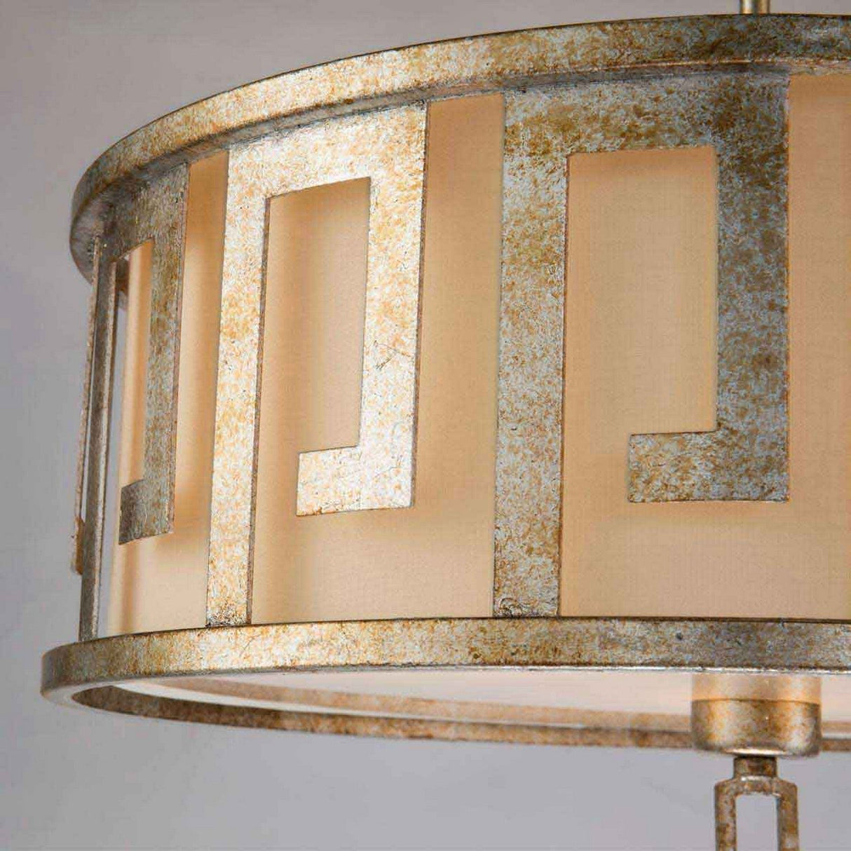 Close-up of a metallic circular lampshade showcasing a geometric pattern with rectangular cutouts. The Lemuria 3 Light Duo-Mount Large Pendant/Semi-Flush in gold with an ivory shade exudes elegance, revealing warm light through the beige inner lining and offering adjustable rods for versatile placement.