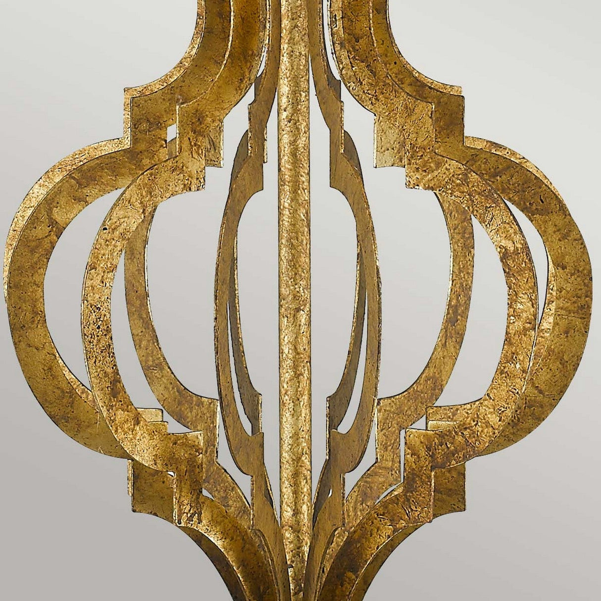Close-up of an ornate, symmetrical golden metal design that mirrors the intricate frame of the Octavia 1 Light Table Lamp - Gold With Ivory Shade, showcasing interlocking geometric patterns. The elegant design is highlighted against a plain gray background, hinting at an ivory shade that complements the gold frame.