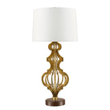 The Octavia 1 Light Table Lamp - Gold With Ivory Shade showcases an ornate gold metal base adorned with intricate scroll designs. It is topped with a cylindrical ivory linen shade and is elegantly supported by a round brown base, creating a stunning focal point in any room.