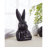 Gopeng Rabbit Ornament 23.2cm in Black, a sculpted figurine of a rabbit in a bow tie and jacket with folded arms, displayed on a table near a book and decorative eggs.