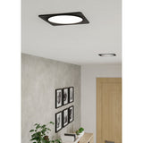Gosmelle 10.5W black square LED downlight with round white diffuser, recessed in a hallway ceiling near artwork and a wooden door.