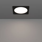 Gosmelle LED downlight with square black plastic trim and round white diffuser, recessed in a grey ceiling, illuminating the space below.