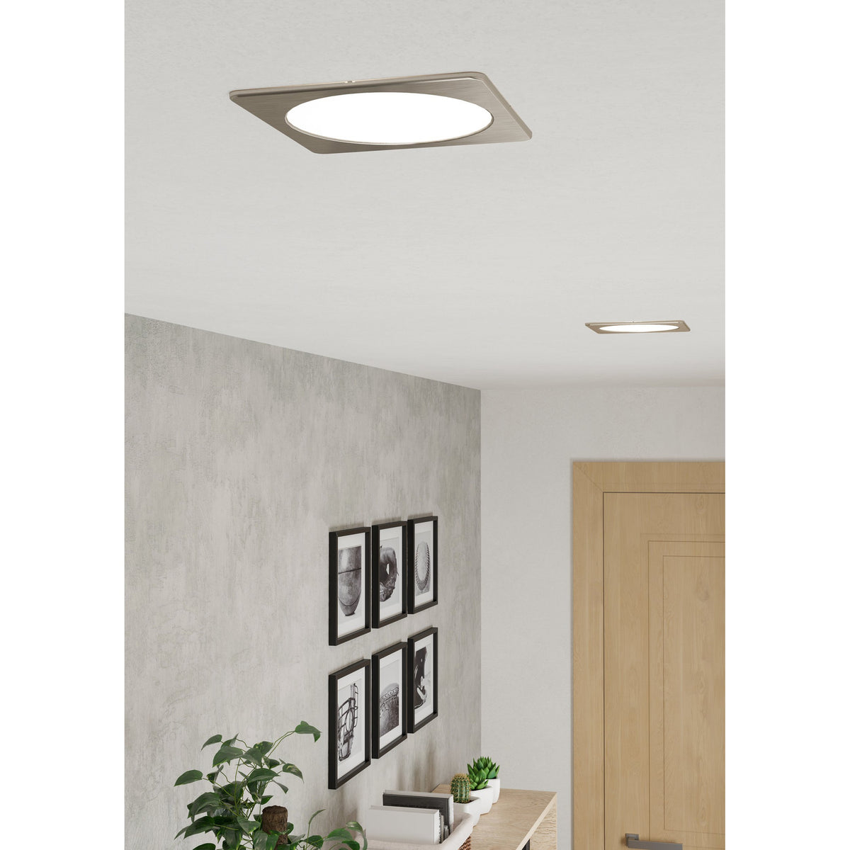 Gosmelle square LED downlight in satin nickel with round white diffuser, shown recessed in a hallway ceiling near a smaller matching downlight.