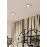 Gosmelle LED Downlight, 11.7 x 11.7cm square recessed fixtures with satin nickel bezels and round white diffusers, shown installed in a ceiling above a wood-slat wall and shelving unit.