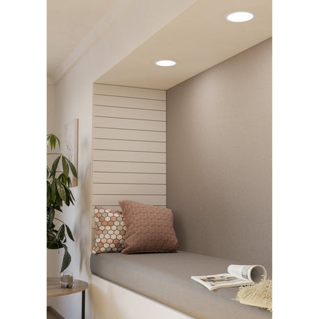 Gosmelle round LED downlight, 11W warm white, white finish, recessed into a ceiling above a window seating nook with cushions and a plant nearby.