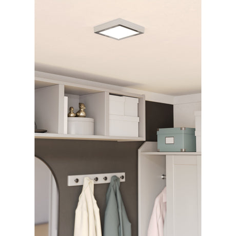 Gosmelle LED Downlight in square chrome-framed design with white diffuser, surface-mounted on a hallway ceiling above open shelving and coat hooks.