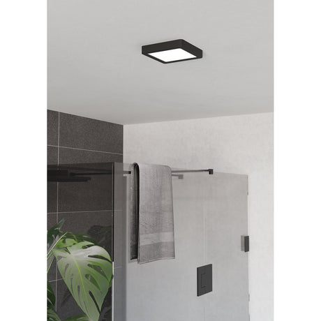 Gosmelle LED Downlight, square black plastic surface-mounted panel with white diffuser, shown on a bathroom ceiling above a glass shower enclosure with a grey towel.
