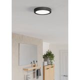 Gosmelle round LED downlight with black plastic body and white diffuser, surface-mounted on a bathroom ceiling above a mirror and vanity unit.