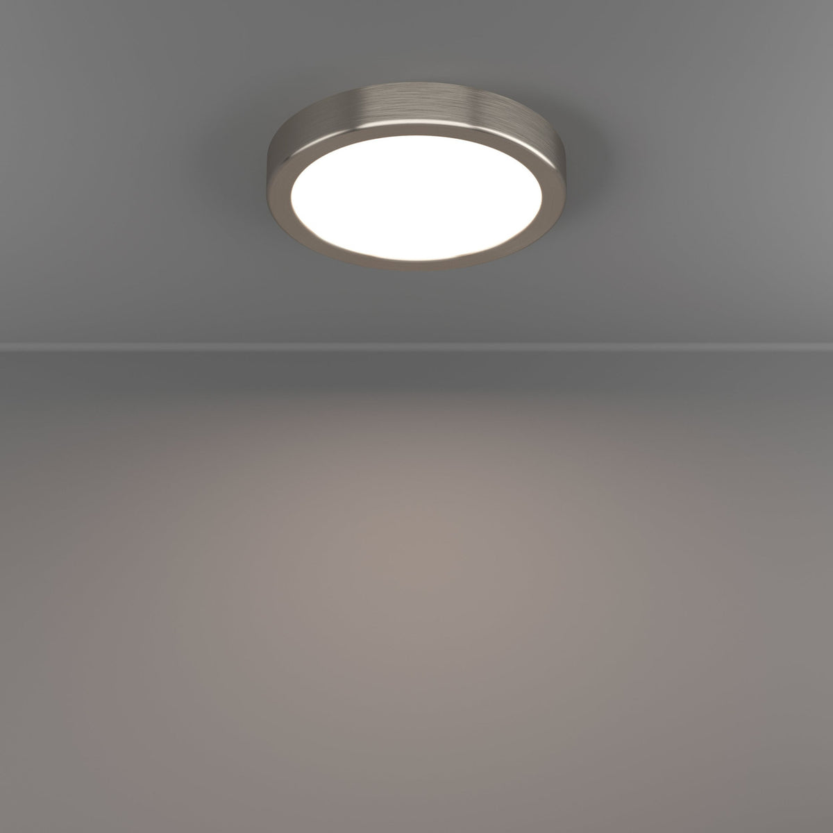Gosmelle LED downlight in satin nickel, round low-profile ceiling fixture with white diffuser, shown illuminated on a grey ceiling and wall.