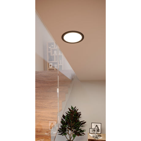 Gosmelle LED Downlight 16.8cm IP20 in black, recessed into a sloped ceiling above a staircase with glass balustrade, illuminating a landing area.