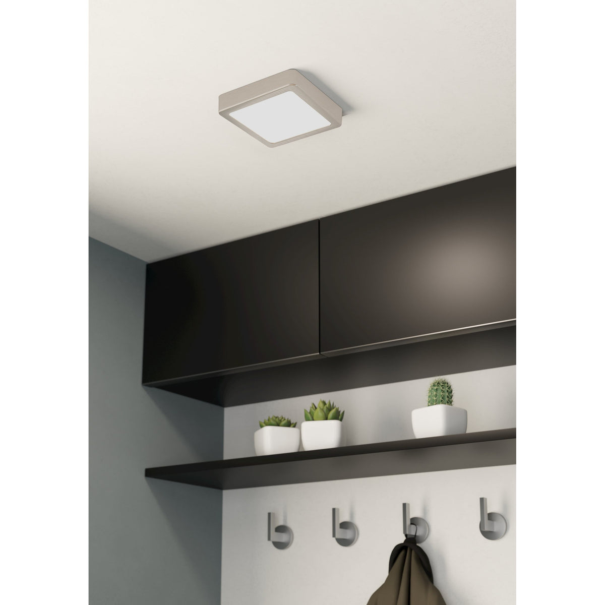 Gosmelle LED Downlight, a square 16 x 16cm ceiling fixture with satin nickel frame and white diffuser, shown mounted above dark cabinetry in a hallway setting.
