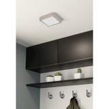 Gosmelle LED Downlight, a square 16 x 16cm ceiling fixture with satin nickel frame and white diffuser, shown mounted above dark cabinetry in a hallway setting.