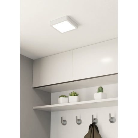 Gosmelle square LED downlight in white, 16 x 16cm flush ceiling fitting shown mounted in a hallway above white cabinetry with a shelf and coat hooks.