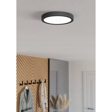 Gosmelle round LED downlight with black plastic trim and white diffuser, mounted flush on a white ceiling above a hallway with wooden panelling and coat hooks.