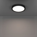 Round Gosmelle LED downlight with black plastic trim and white diffuser, mounted on a grey ceiling, illuminating the room below with warm white light.