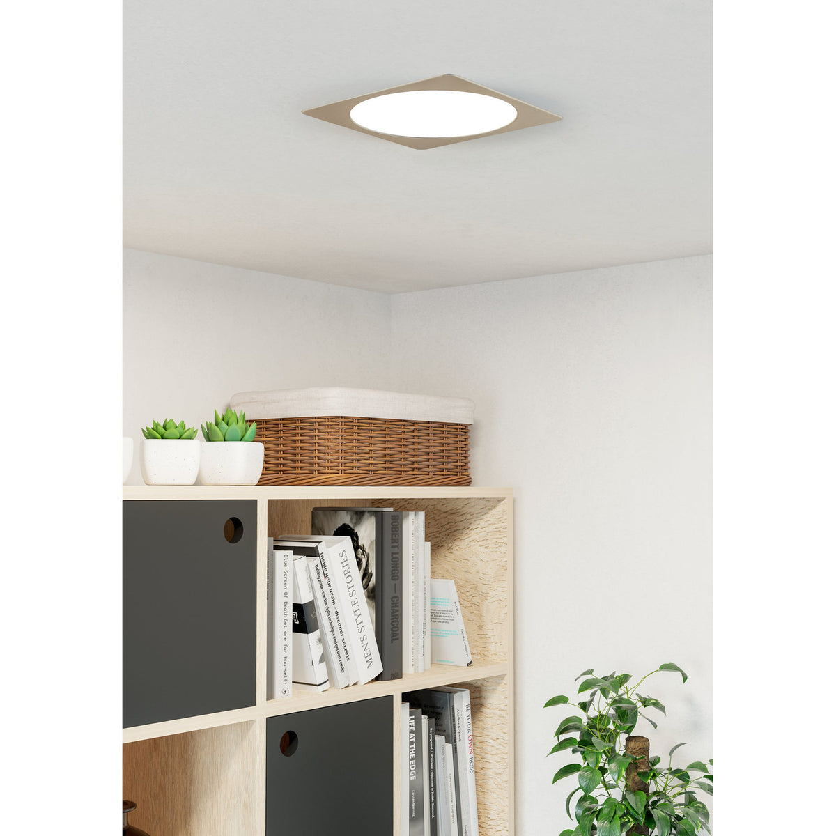 Gosmelle LED Downlight 21.6cm in satin nickel with square trim and round white diffuser, shown ceiling-mounted above a bookshelf in a living room.