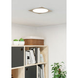 Gosmelle LED Downlight 21.6cm in satin nickel with square trim and round white diffuser, shown ceiling-mounted above a bookshelf in a living room.