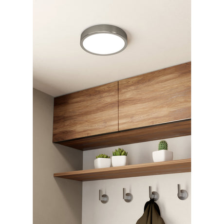Gosmelle round LED ceiling downlight in satin nickel with white diffuser, shown on a hallway ceiling above wood cabinetry and an open shelf.