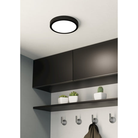 Gosmelle LED Downlight 21cm, round black steel fixture with white diffuser, mounted flush on a white ceiling above dark cabinetry in a hallway setting.