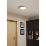 Gosmelle LED Downlight in satin nickel with a round white diffuser, mounted flush on a hallway ceiling above a wooden door and black cabinetry.