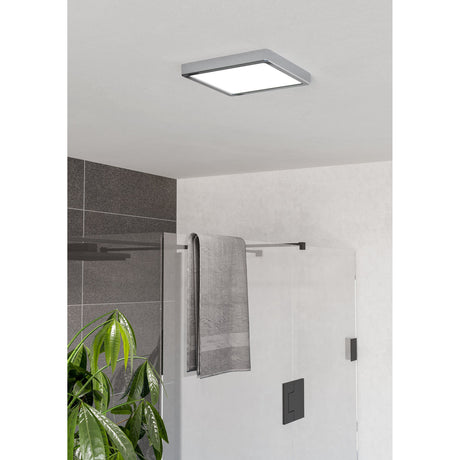 Gosmelle LED Downlight, square chrome-framed ceiling fixture with white diffuser, mounted flush on a bathroom ceiling near a shower enclosure and towel rail.