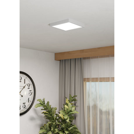 Gosmelle square LED downlight, 22 x 22cm, white plastic frame and diffuser, mounted flush on a ceiling above a curtained window in a living room setting.