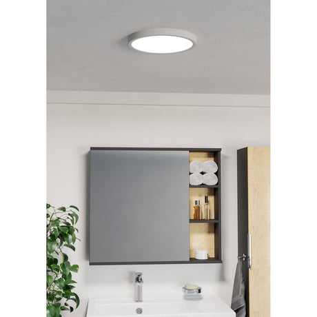 Round white LED downlight, Gosmelle 27.8cm IP44, mounted flat on a bathroom ceiling above a wall mirror with shelving.
