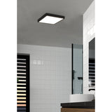 Gosmelle square LED downlight with black steel frame and white diffuser, mounted on a bathroom ceiling, warm white light above a glass shower screen and tiled wall.