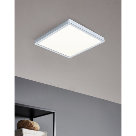 Gosmelle square LED downlight in chrome with white diffuser, flush-mounted on a grey ceiling above a bathroom shelf with towels.