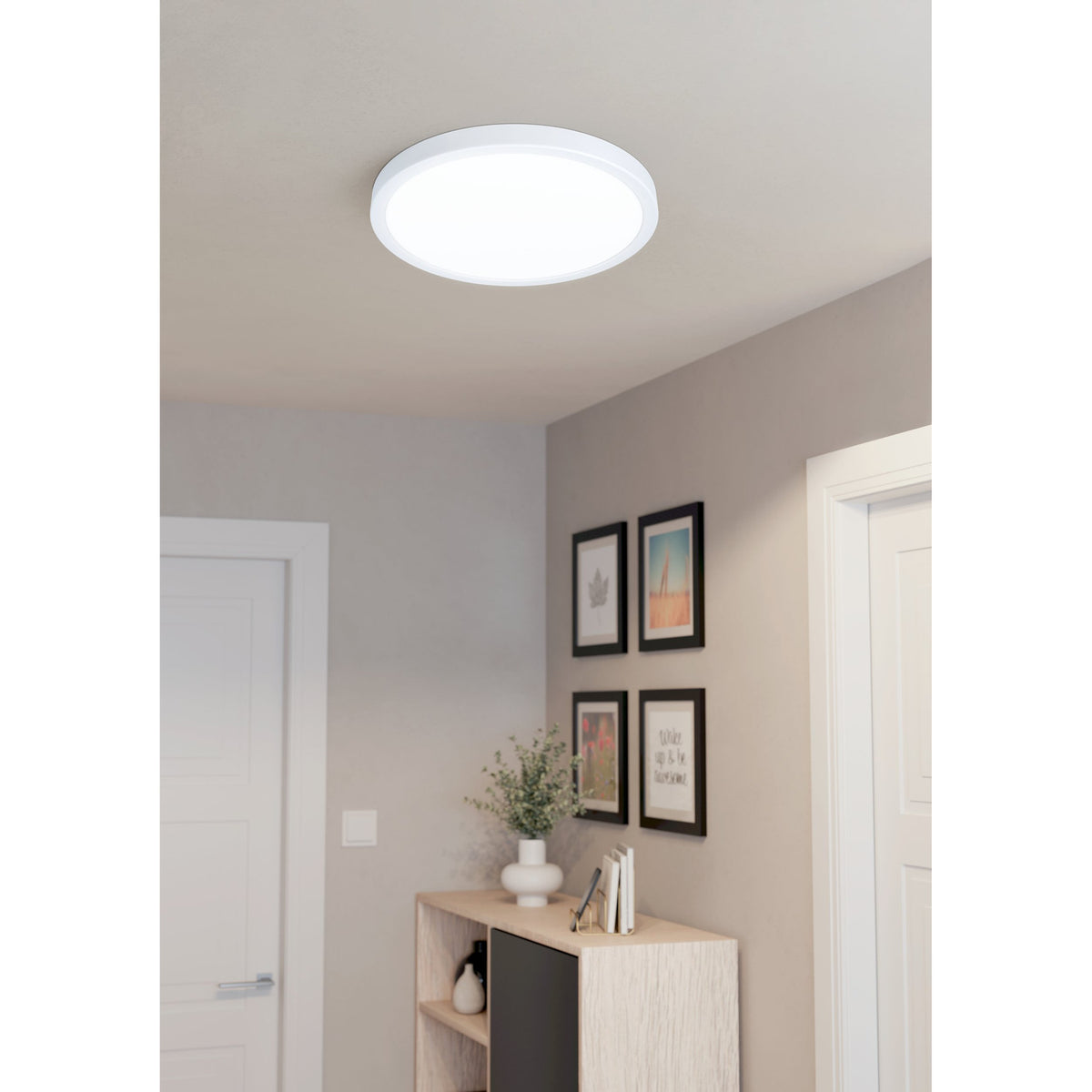 Gosmelle round LED downlight in white steel with a slim plastic diffuser, fitted flush to a hallway ceiling above a gallery wall and console table.
