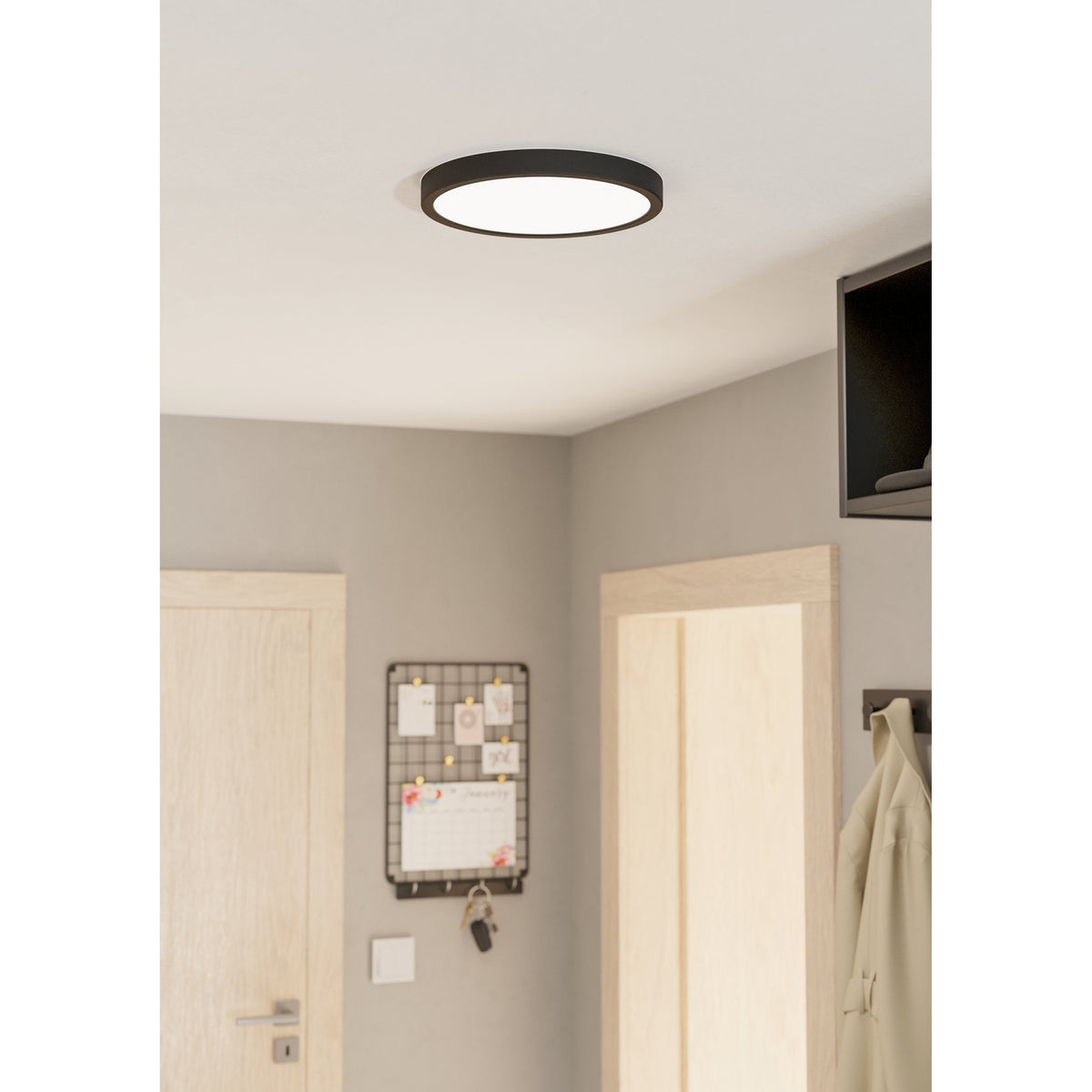 Gosmelle LED Downlight, a slim round ceiling fixture with black steel rim and white diffuser, shown mounted flush on a white ceiling in a hallway setting.