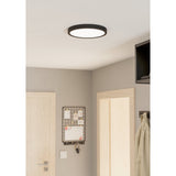 Gosmelle LED Downlight, a slim round ceiling fixture with black steel rim and white diffuser, shown mounted flush on a white ceiling in a hallway setting.