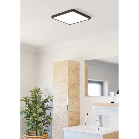 Gosmelle LED Downlight 29 x 29cm IP44 in black, square ceiling fixture with white diffuser, shown installed in a bathroom ceiling above a washbasin and mirror.