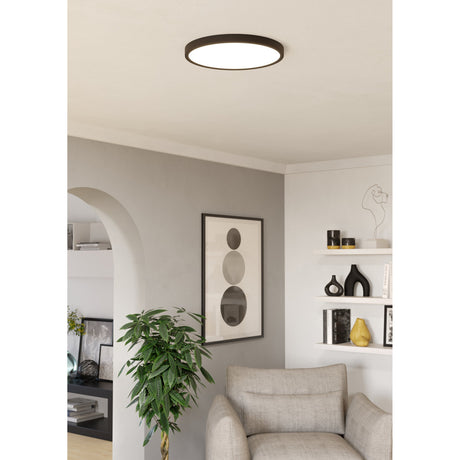 Gosmelle LED Downlight 38.9cm in black, a slim round ceiling fixture with a black rim and white diffuser, shown illuminating a neutral-toned living room.
