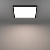 Gosmelle LED Downlight 39 x 39cm in black, a slim square ceiling panel with black plastic frame and white diffuser, shown glowing warm white on a grey ceiling.