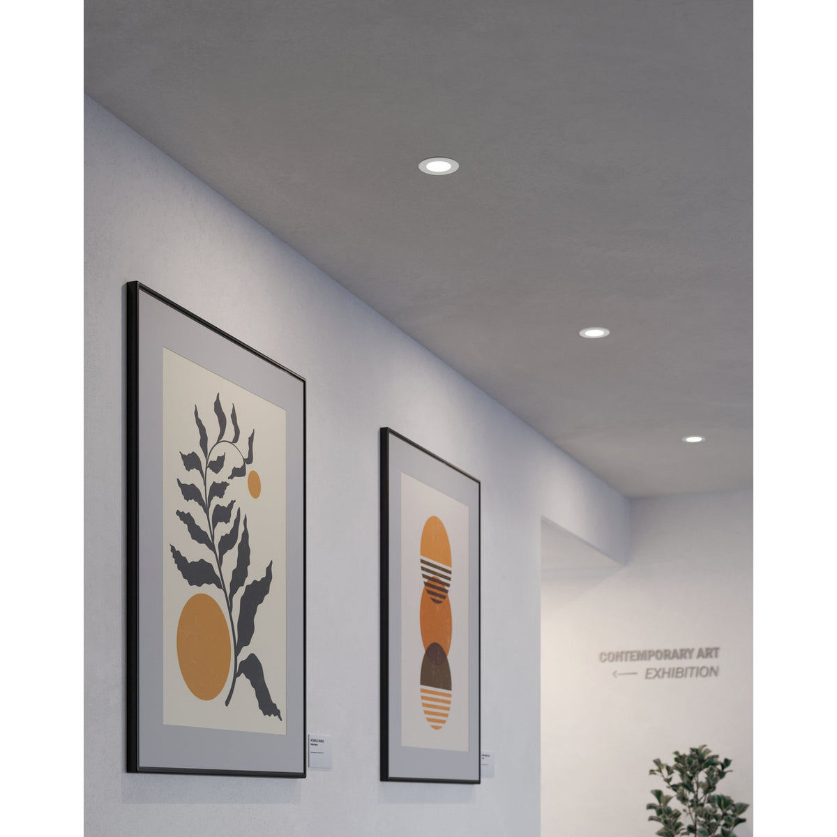 Gosmelle round LED downlight in white recessed flush into a hallway ceiling, shown alongside framed artwork and a plain light grey wall.