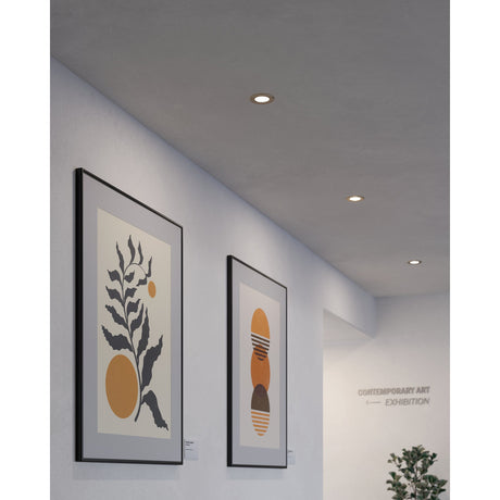 Gosmelle LED downlights in satin nickel recessed into a grey hallway ceiling, lighting framed abstract artwork near a gallery entrance.