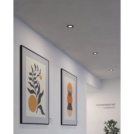 Gosmelle LED Downlights, 8.6cm black steel trims, recessed into a grey ceiling above framed artwork in a gallery-style hallway.