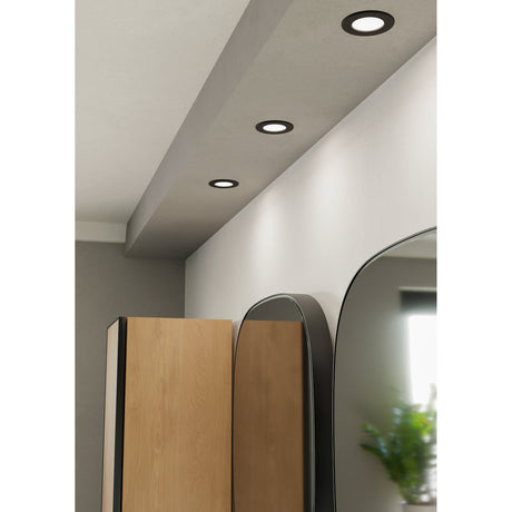 Gosmelle LED Downlight 8.8cm IP44 in black, shown recessed into a hallway ceiling with matching units illuminating a space near a wall mirror and wooden wardrobe.