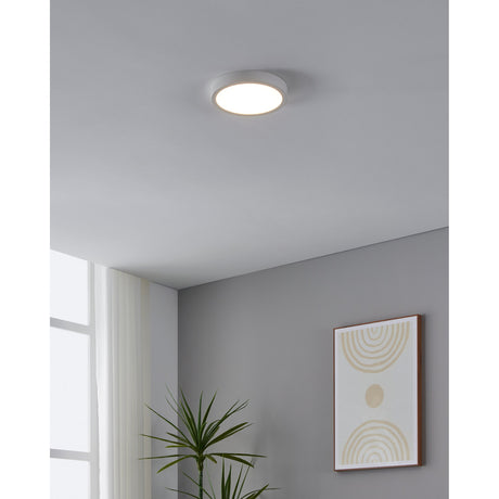 Gosmelle round LED flush ceiling light in white, 21cm diameter, mounted on a grey ceiling in a hallway setting near a wall mirror and artwork.