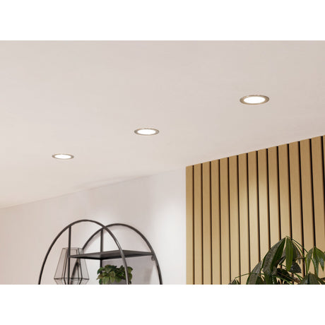 Gosmelle Smart LED Downlights, 12cm round satin nickel bezels recessed into a white ceiling, shown lit in a living space with wood slat panelling and plants nearby.
