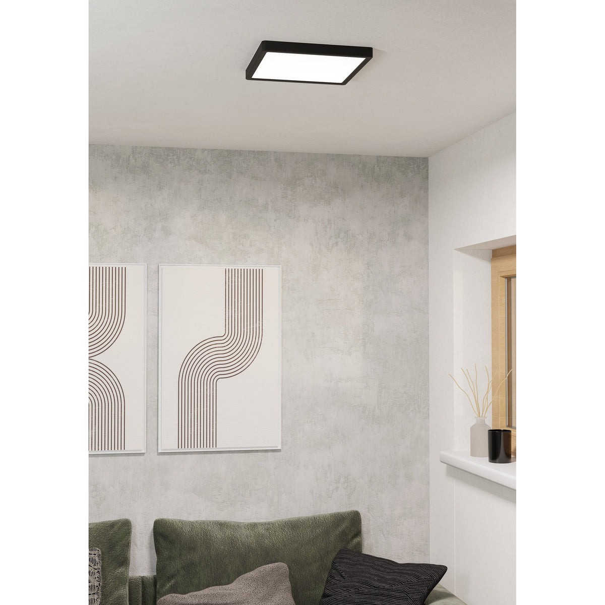 Gosmelle square LED downlight, 29 x 29cm, with black plastic frame and white diffuser, mounted flush on a living room ceiling above a grey wall with framed art and a green sofa.
