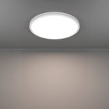 Gosmelle round LED downlight, 38.9cm white plastic fitting flush-mounted on a grey ceiling, illuminated with warm white light across the room below.