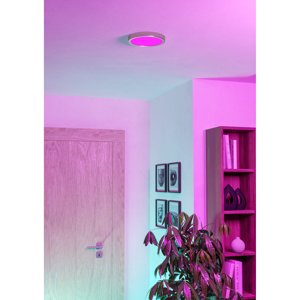 Gosmelle Smart LED Downlight 21.1cm in satin nickel finish, round ceiling-mounted fixture glowing pink, shown in a hallway with doorway, framed art, and shelving.