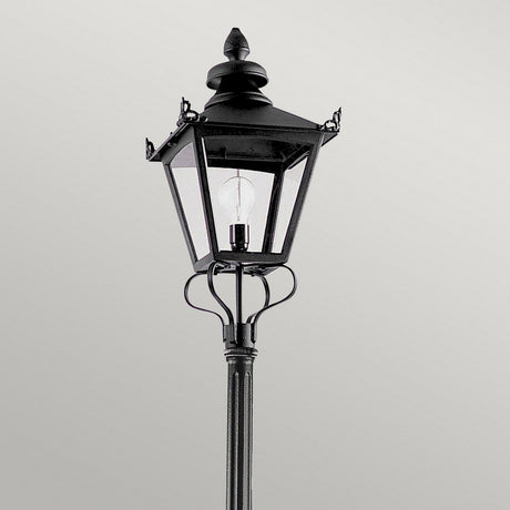 A black street lamp with a vintage design, made from cast aluminium and featuring a clear glass enclosure and visible bulb, similar to the Grampian 1 Light Lamp Post - Black, ideal for elevating your outdoor lighting against a plain gray backdrop.