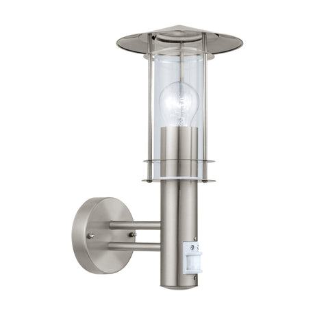 Granette outdoor wall light in stainless steel, with hat-shaped cap, clear glass cylinder shade, exposed bulb, motion sensor, and round wall plate on two arms, shown on a white background.