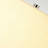 Close-up of a fabric surface in a soft grey/brown hue, possibly from a Grange Park 1 Light Table Lamp, featuring a small metallic knob extending from the top edge. The image captures ambient lighting with its gentle, neutral color tones.