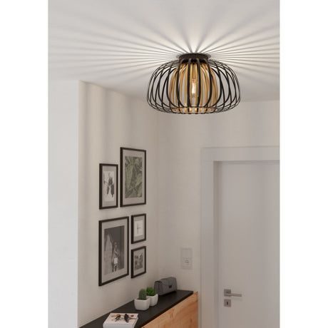 Grilvessa Ceiling Light in black and gold, a flush-mount fixture with layered flat-steel cages casting radiating light patterns, shown above a hallway with framed artwork and a sideboard.