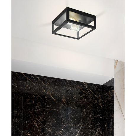 Gromora square flush ceiling light in black steel with clear glass panels, mounted on a white ceiling above a black marble wall, fitted with two exposed E27 bulbs.