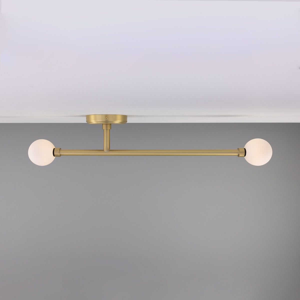 Gunning Twin Glass Globe Semi Flush Ceiling Light IP44 in satin brass, with two opal glass globes on a slim horizontal bar, mounted close to a white ceiling.